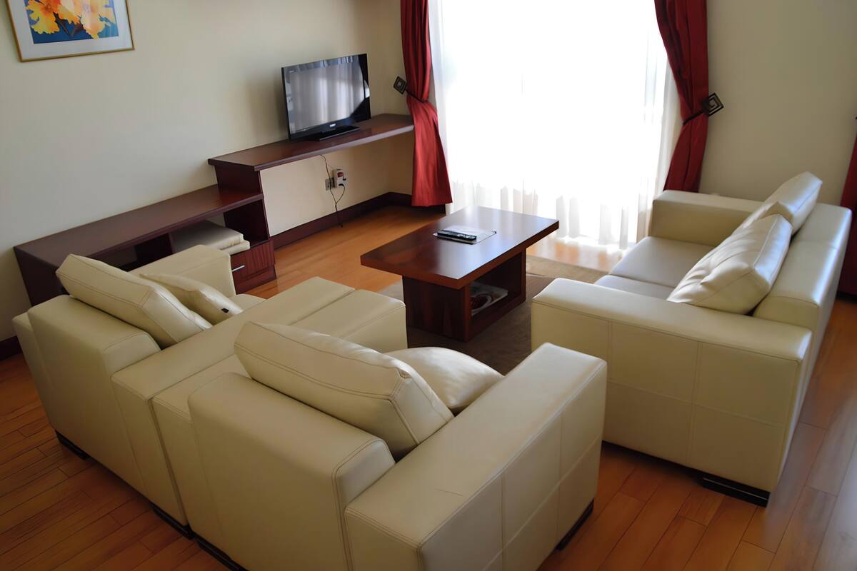 A modern living room with a sofa set, a coffee table, and a TV on a wooden stand.