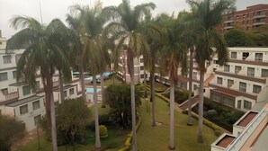 A residential complex with multiple buildings, palm trees, and a swimming pool.