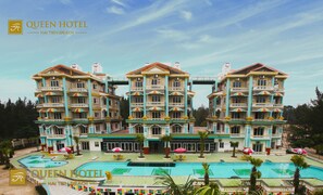 A large, multi-story hotel with a central swimming pool and multiple balconies.