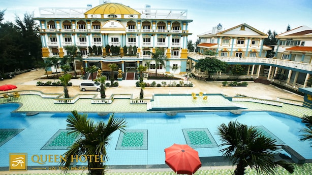A hotel with a large swimming pool, multiple balconies, and a well-maintained garden.