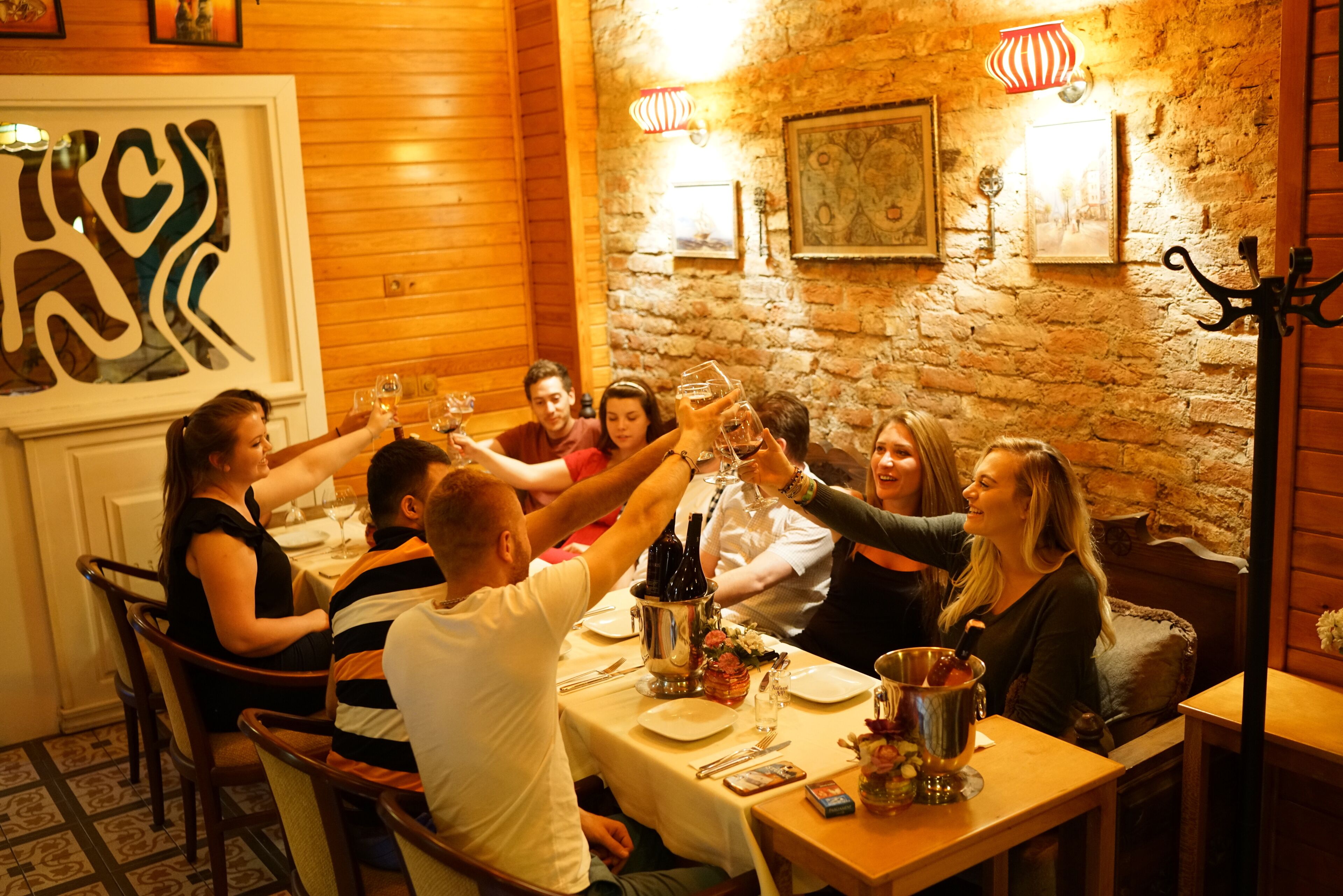 A group of people toasting at a table in a room with wooden walls and a tiled floor.