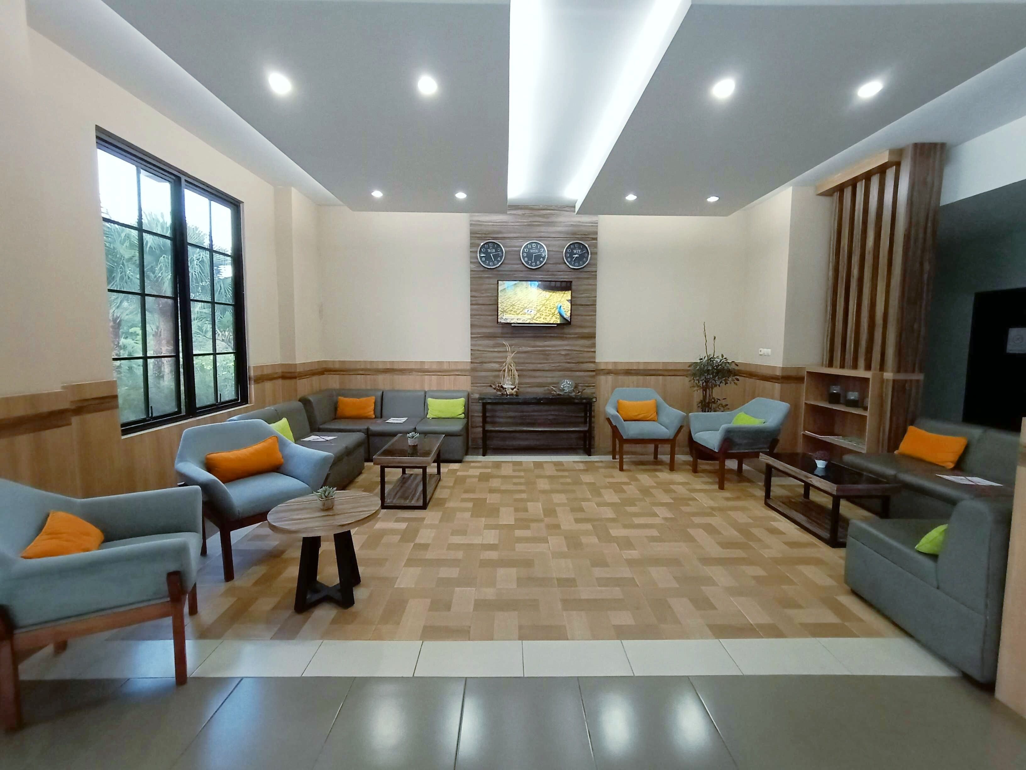 A modern living room with a sectional sofa, armchairs, a coffee table, and a TV mounted on the wall.