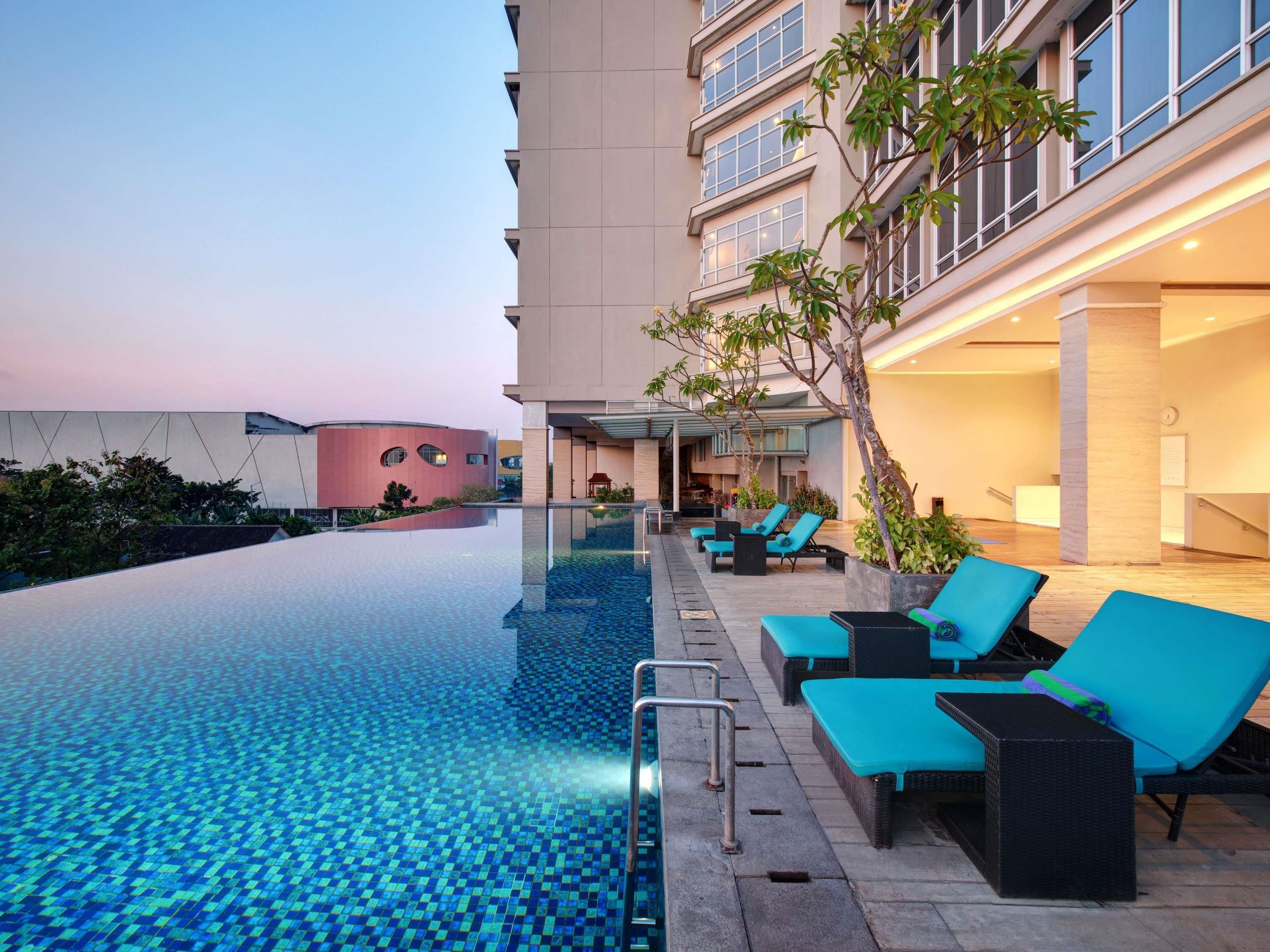 A hotel pool area with lounge chairs and a building in the background.