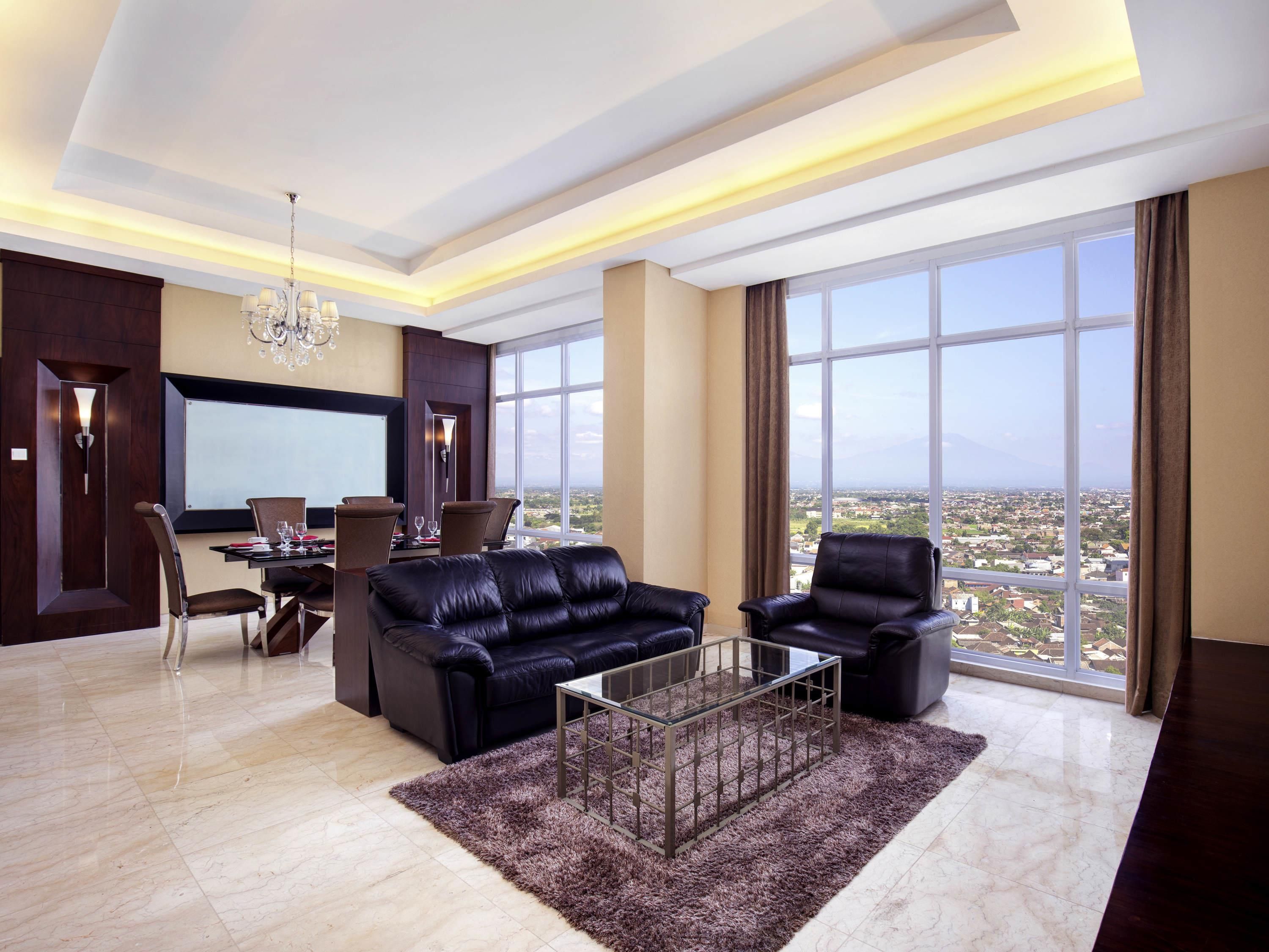 A modern living room with a large window, a chandelier, and a dining area.