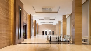 A modern hotel lobby with a long corridor, escalators, and a chandelier. - Grand Mercure Solo Baru (Grogol)