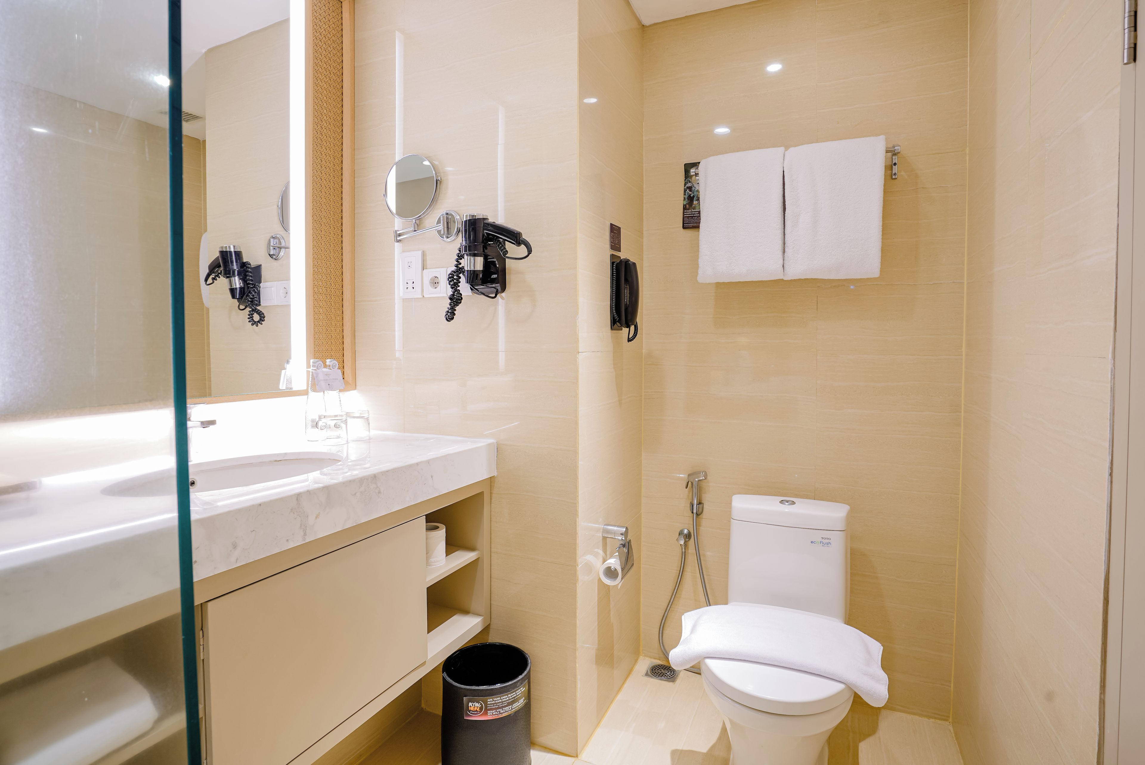 A modern bathroom with a glass partition, a white sink, a toilet, and a shower area.