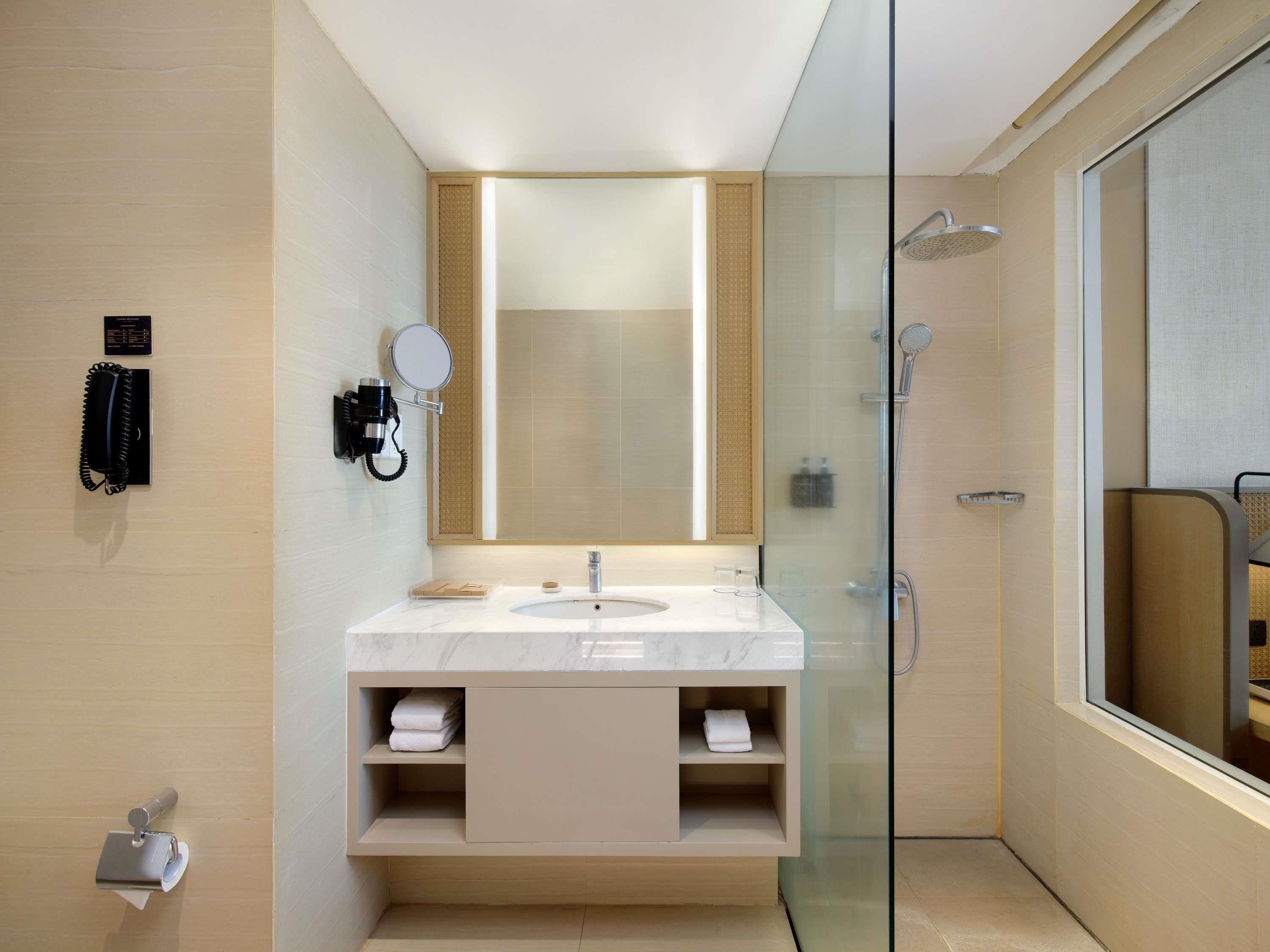 Un baño moderno con cabina de ducha de vidrio, lavamanos de mármol y un espejo grande.