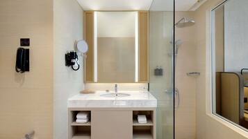 Un baño moderno con cabina de ducha de vidrio, lavamanos de mármol y un espejo grande.