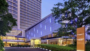 A modern hotel with a large entrance, a prominent sign, and a parking area. - Grand Mercure Solo Baru (Grogol)