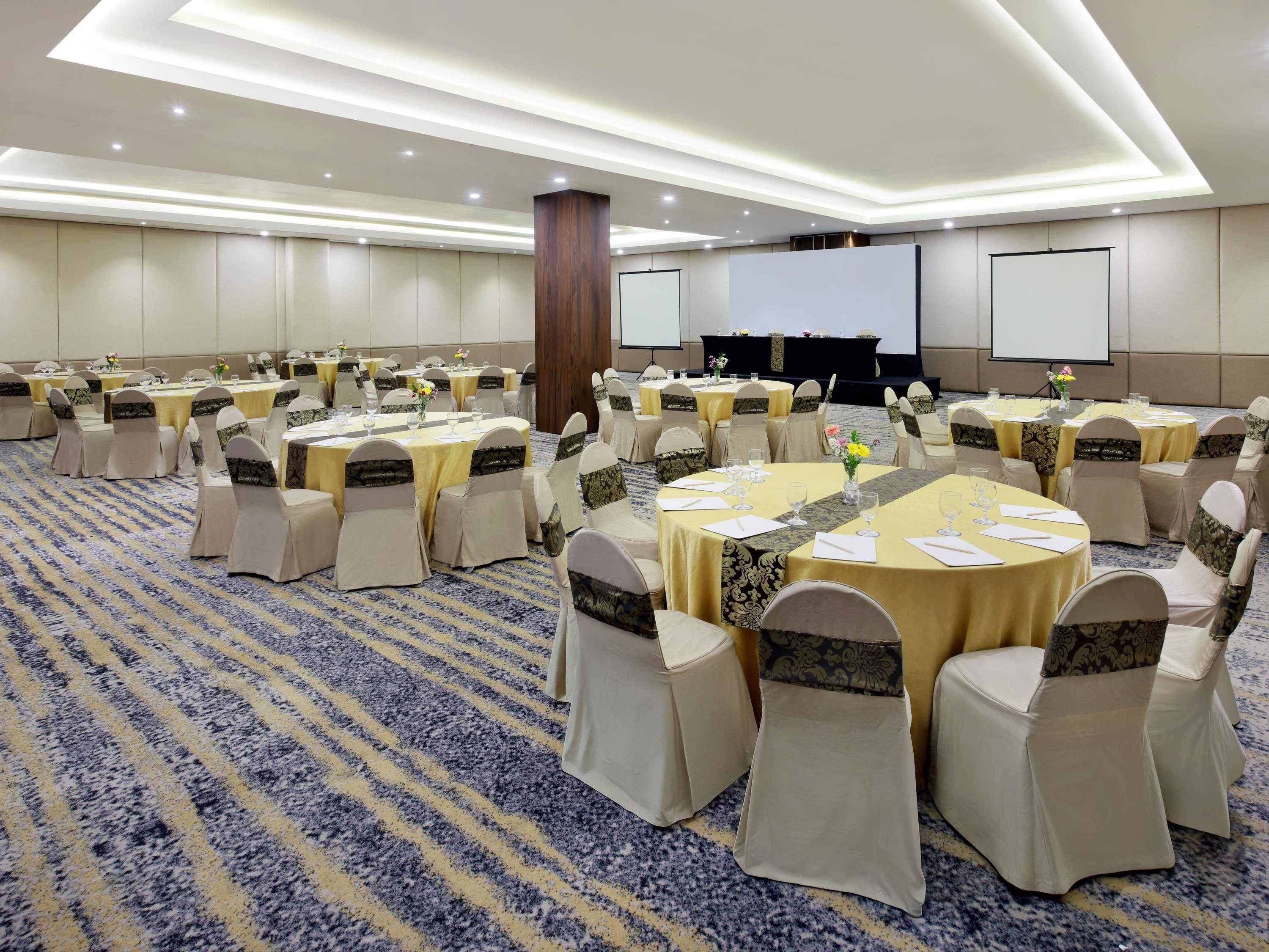 A conference room with round tables, chairs, and a presentation screen.