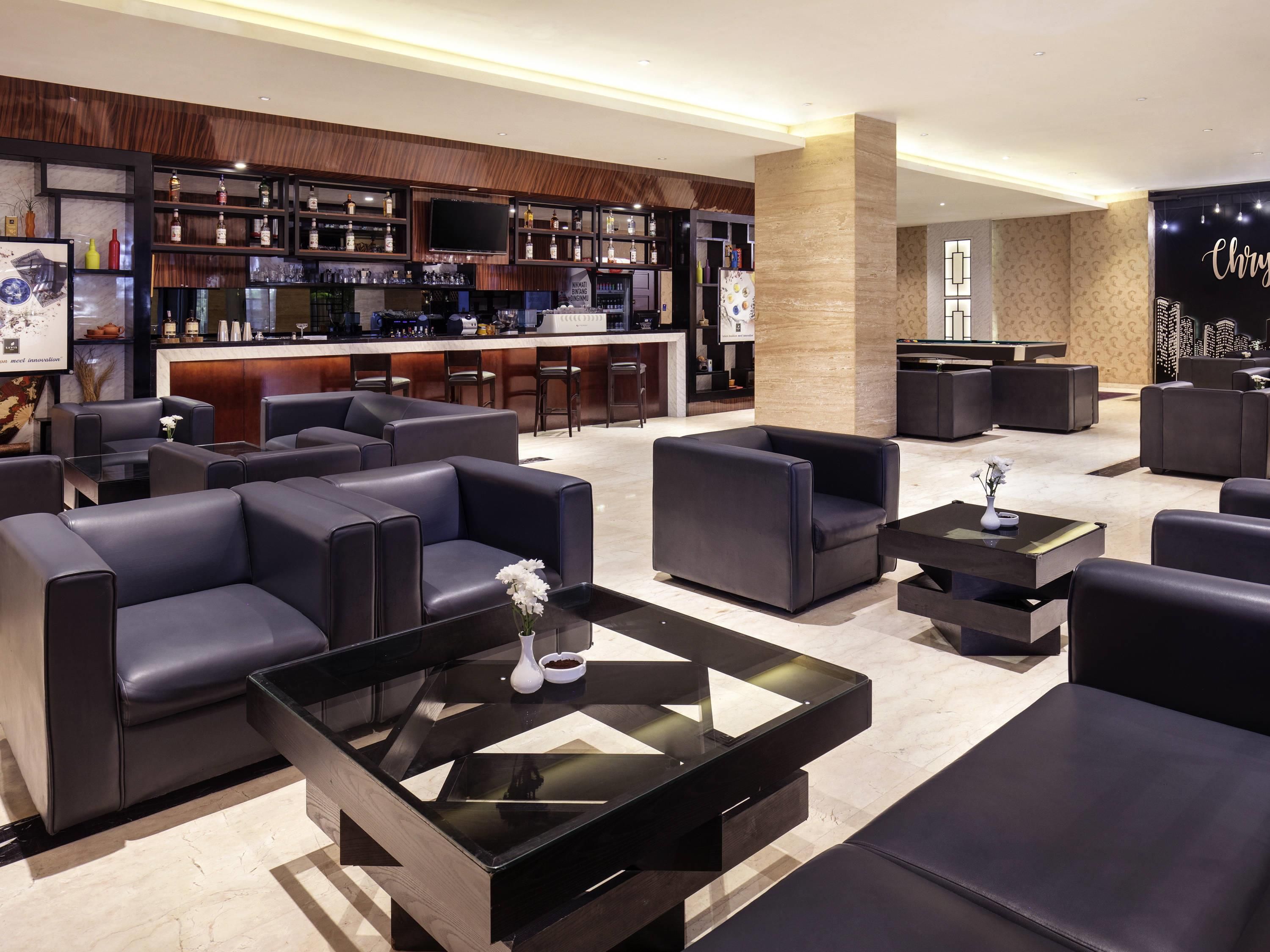 A modern lounge area with leather sofas, a bar with a variety of liquor bottles, and a large screen.