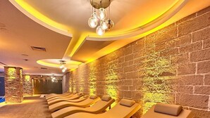 A spa room with multiple sun loungers, a stone wall, and a ceiling light fixture. - Ramada by Wyndham Istanbul Merter (Istanbul)