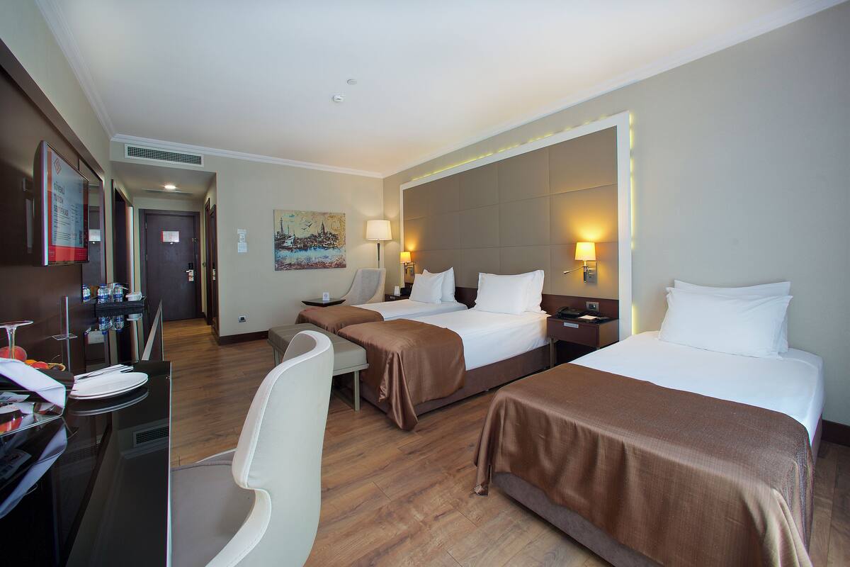 A hotel room with two beds, a desk with a chair, and a large mirror.