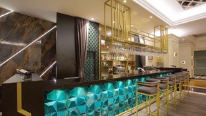 A bar area with a geometric tile backsplash, a bar counter, and multiple stools. - Ramada by Wyndham Istanbul Merter (Istanbul)