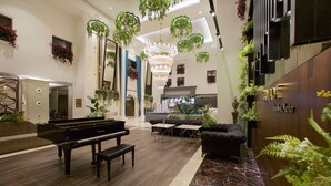 A spacious lobby with a grand piano, comfortable seating, and lush green plants. - Ramada by Wyndham Istanbul Merter (Istanbul)