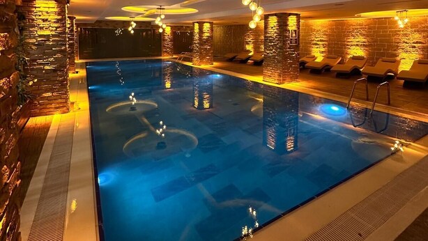 A swimming pool with a brick wall on one side and a lounge area with chairs on the other. - Ramada by Wyndham Istanbul Merter (Istanbul)
