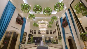A grand lobby with a central chandelier, hanging greenery, and a marble fountain. - Ramada by Wyndham Istanbul Merter (Istanbul)
