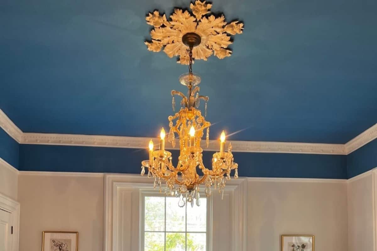 A bedroom with a large bed, a chandelier, two bedside tables with lamps, and a window.