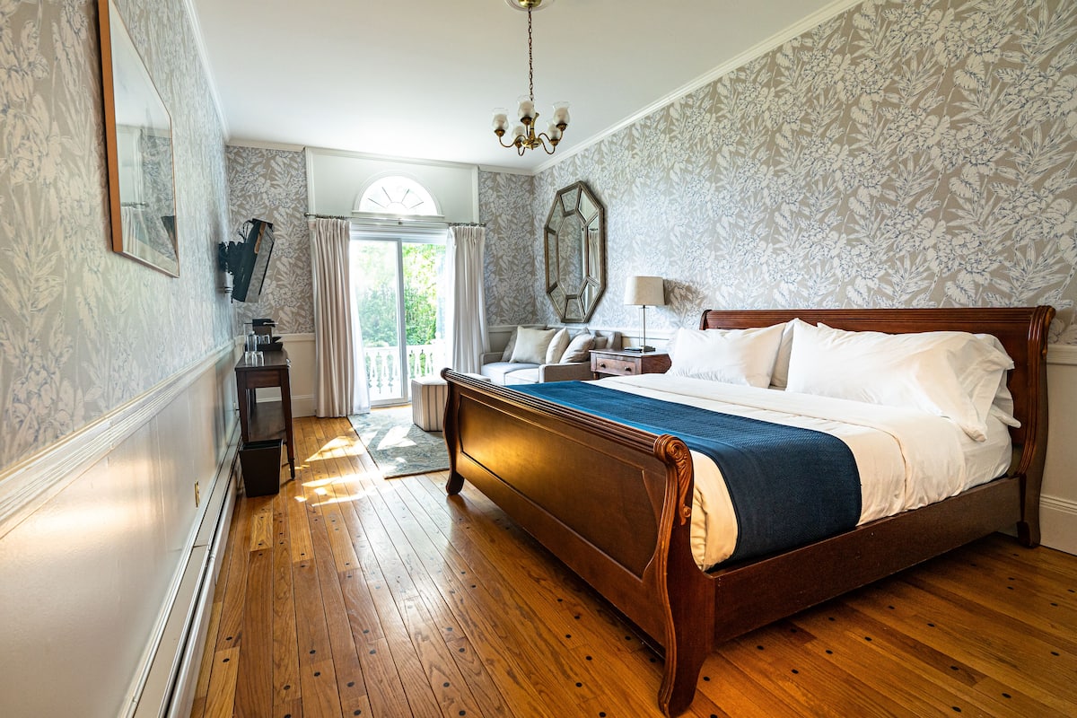 A bedroom with a wooden bed, a nightstand, a dresser, a mirror, and a window with curtains.