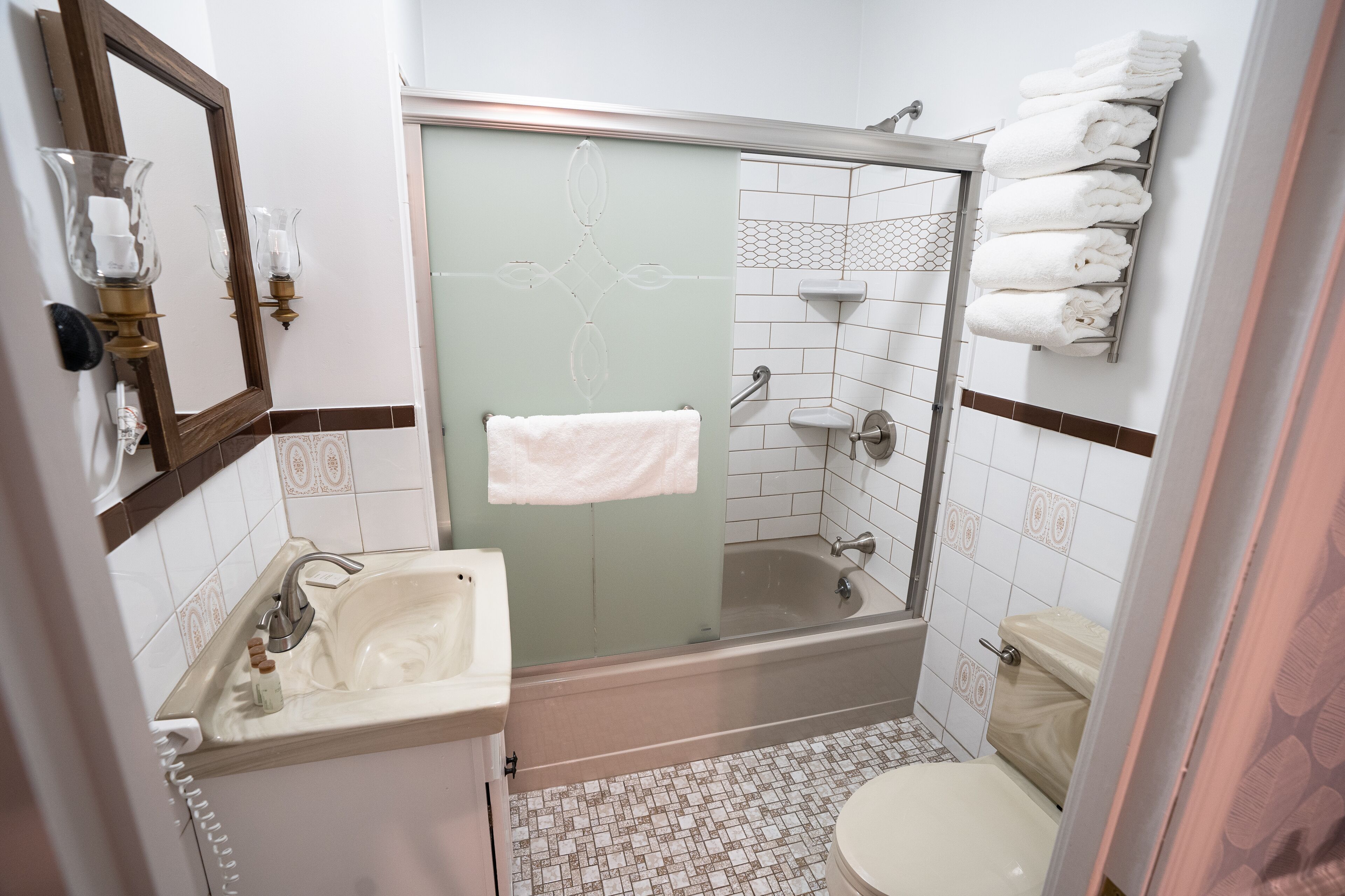 Une salle de bain avec une douche à parois de verre, un lavabo avec un miroir et des toilettes.
