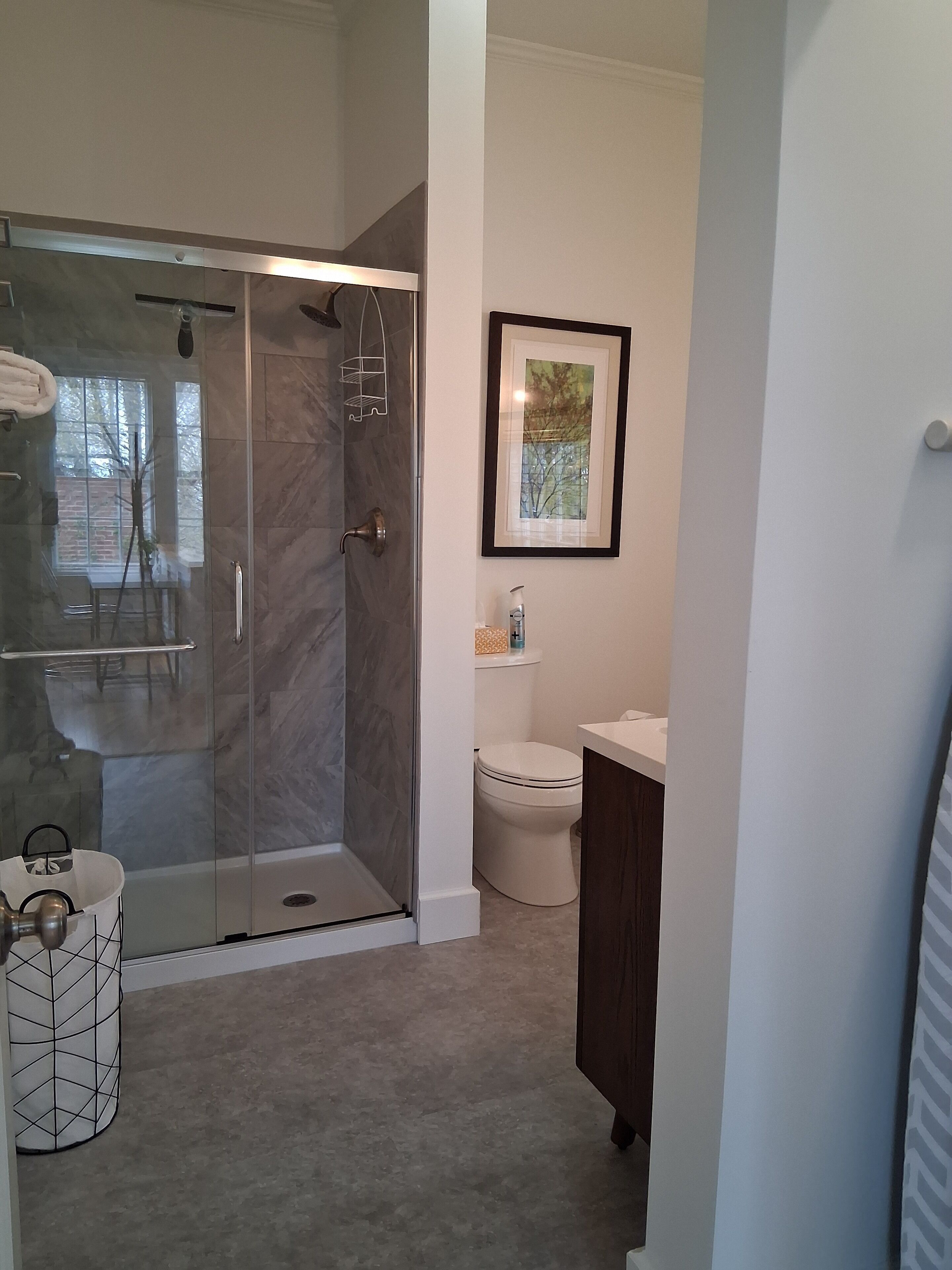 A modern bathroom with a glass-enclosed shower, a toilet, and a sink.