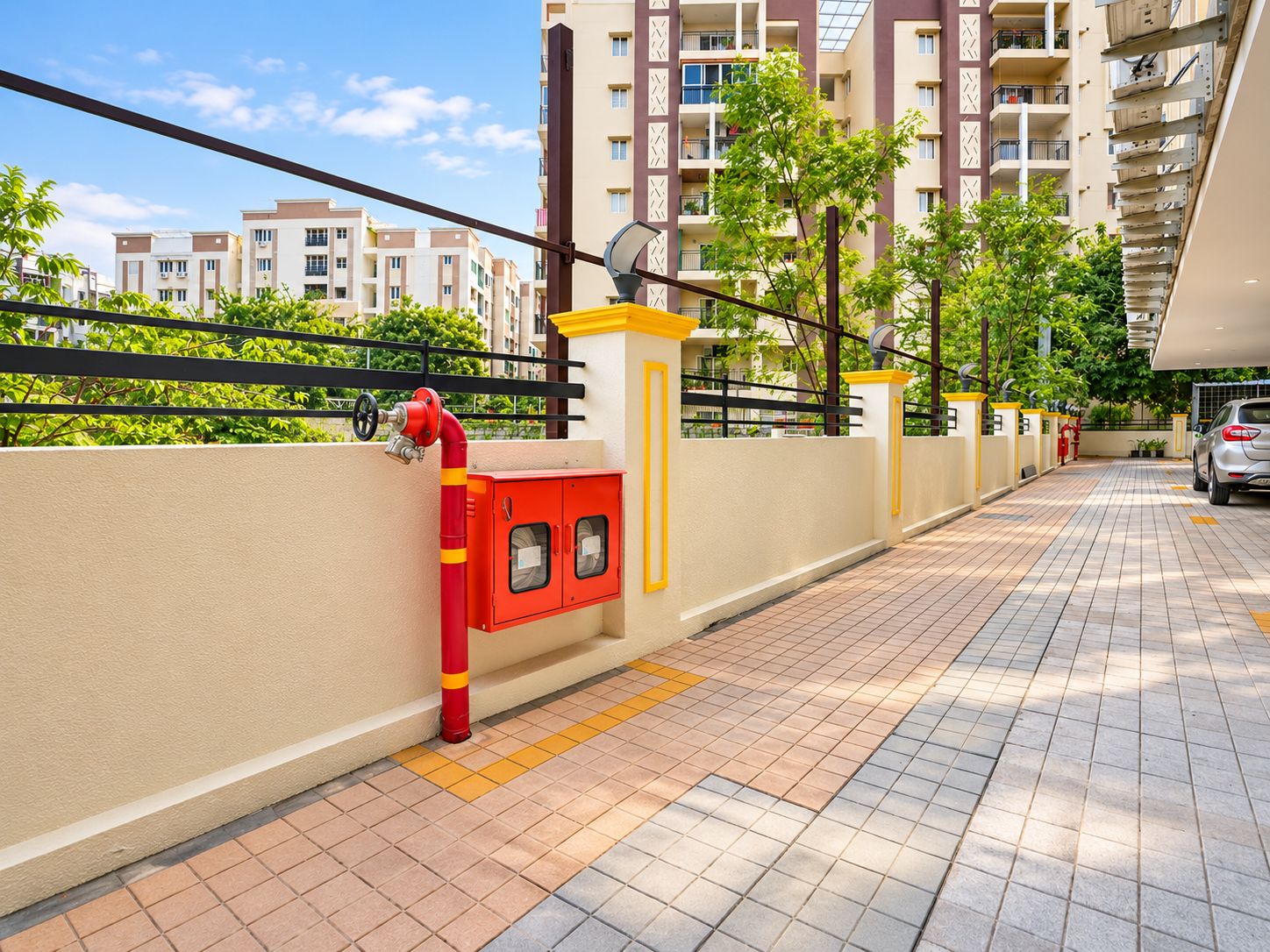 A residential building with a gated entrance, a fire hydrant, and a car parked inside.