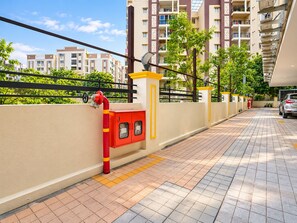 A residential building with a gated entrance, a fire hydrant, and a car parked inside.
