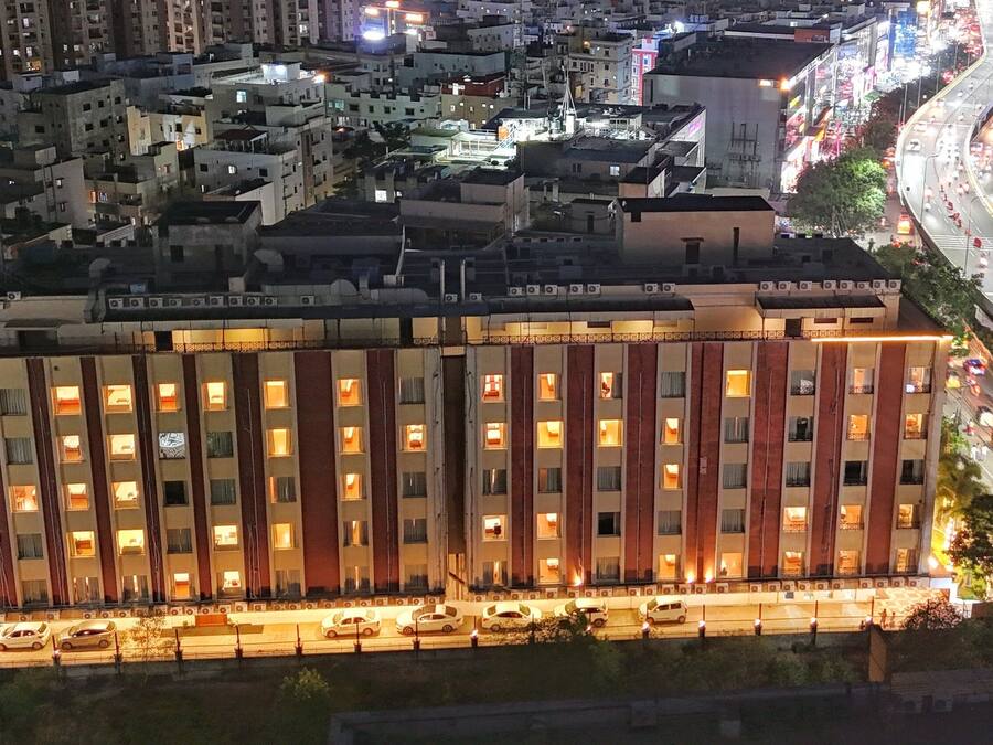 Een meerhoog hotel met een rij kamers, een parkeerplaats en een drukke straat op de achtergrond.