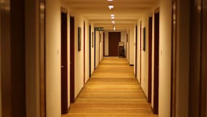 A long, narrow hotel corridor with wooden flooring and doors on both sides. - The Altruist Hitech Hotel (Hyderabad)