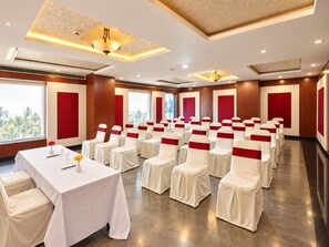A conference room with rows of chairs, a table with a white tablecloth, and red sashes. - The Altruist Hitech Hotel (Hyderabad)