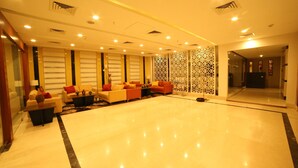 A spacious lobby with a polished marble floor, a seating area with sofas and armchairs, and a decorative partition with intricate patterns. - The Altruist Hitech Hotel (Hyderabad)