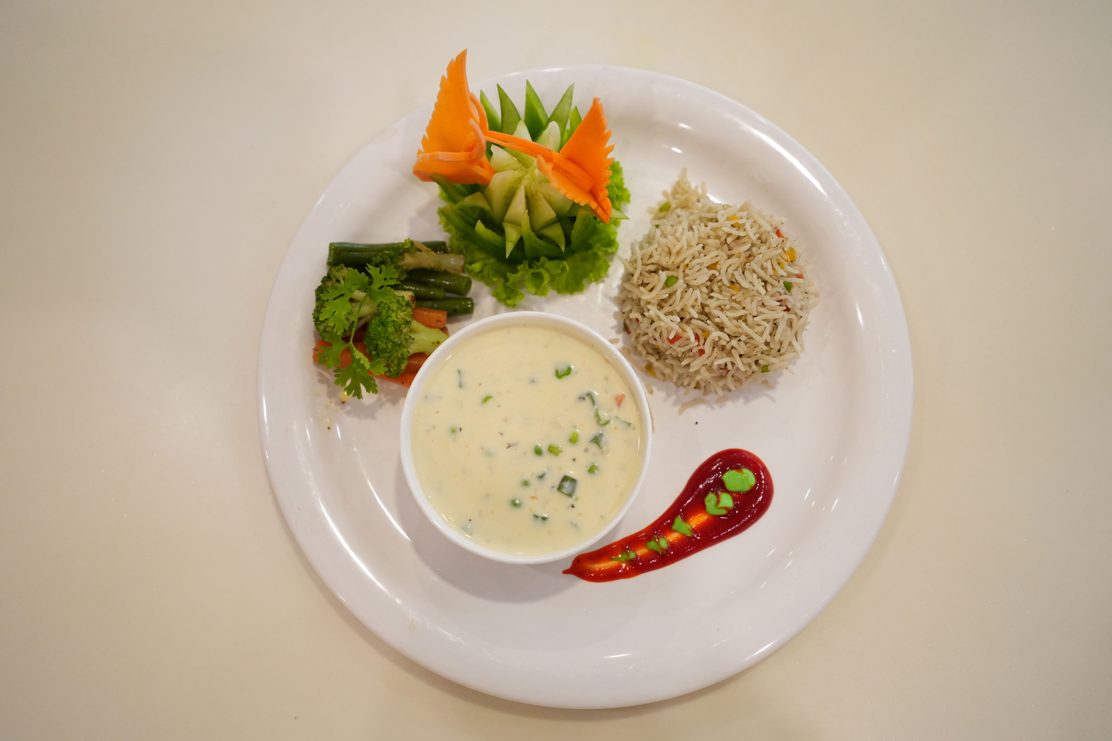 A plate with rice, vegetables, and a bowl of soup.