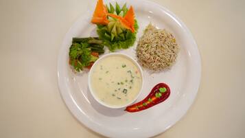 A plate with rice, vegetables, and a bowl of soup.