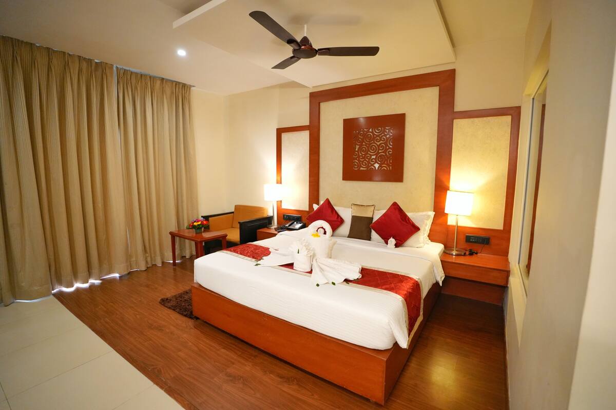 A hotel room with a large bed, two bedside tables, a ceiling fan, and a decorative wall panel.