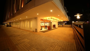 A hotel entrance at night with a tiled walkway and a covered area with a person standing near the entrance. - The Altruist Hitech Hotel (Hyderabad)