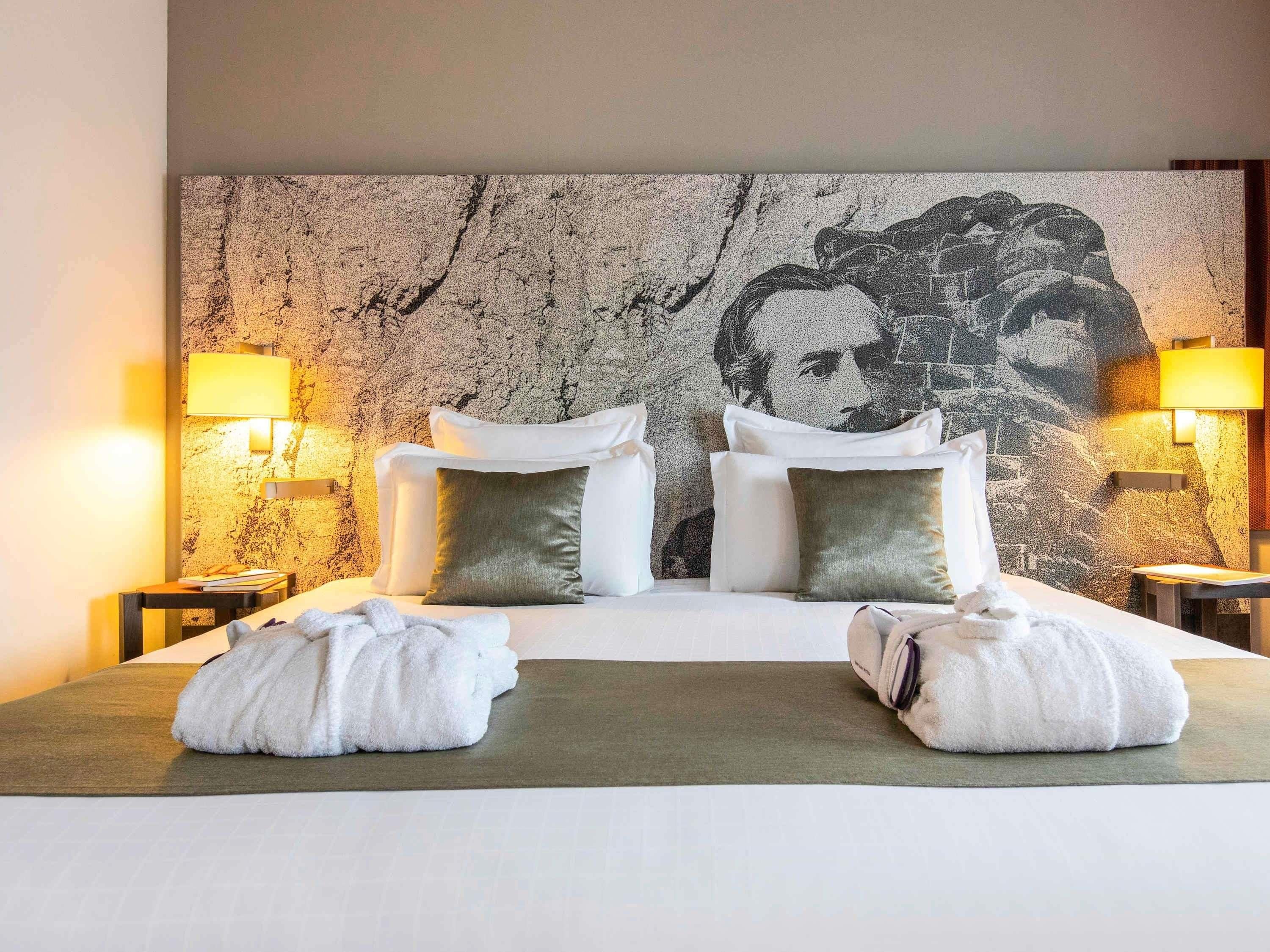 A hotel room with a large bed, two bedside tables, lamps, and a textured wall.