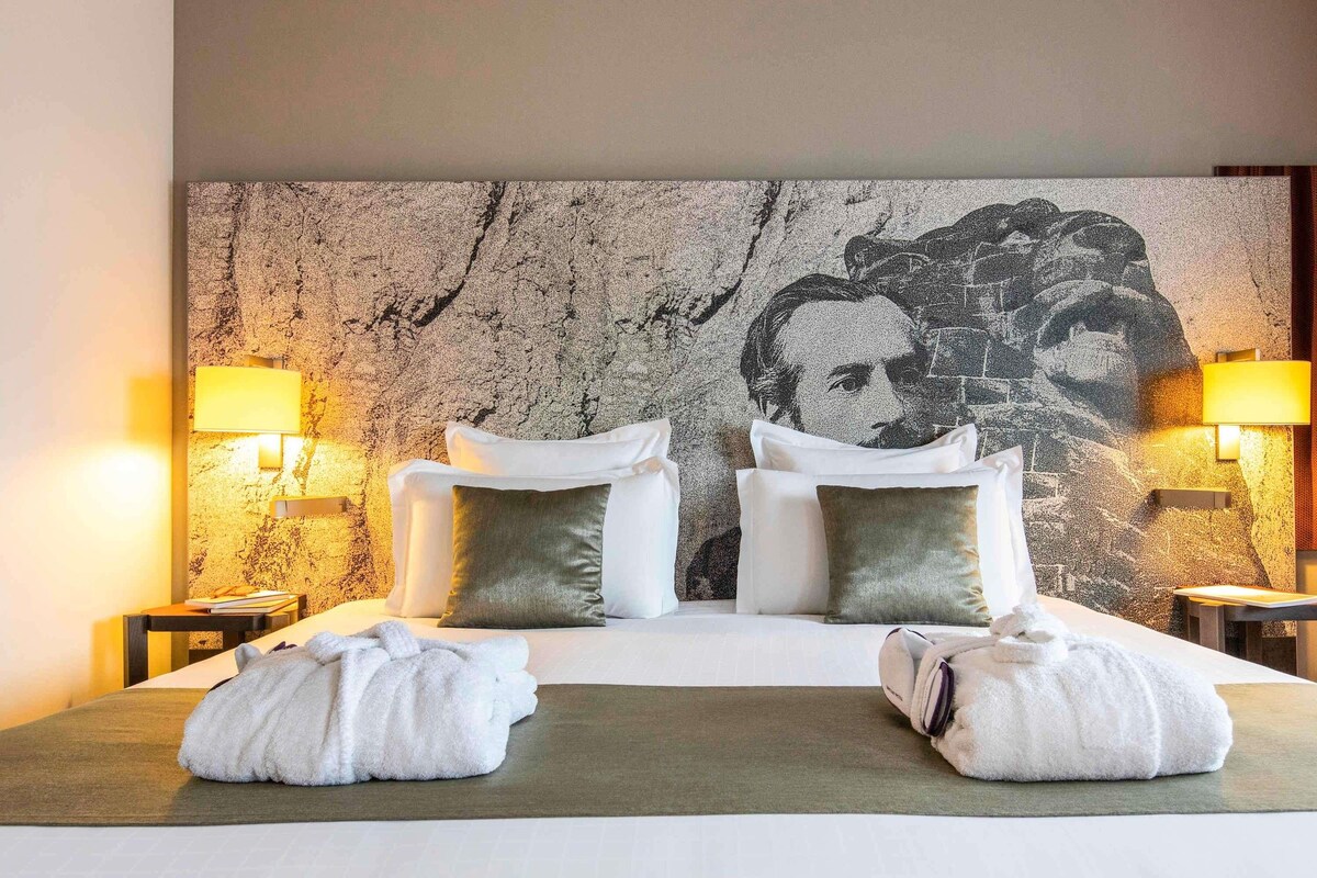 Une chambre d’hôtel avec un grand lit, deux tables de chevet, des lampes et un mur à texture.