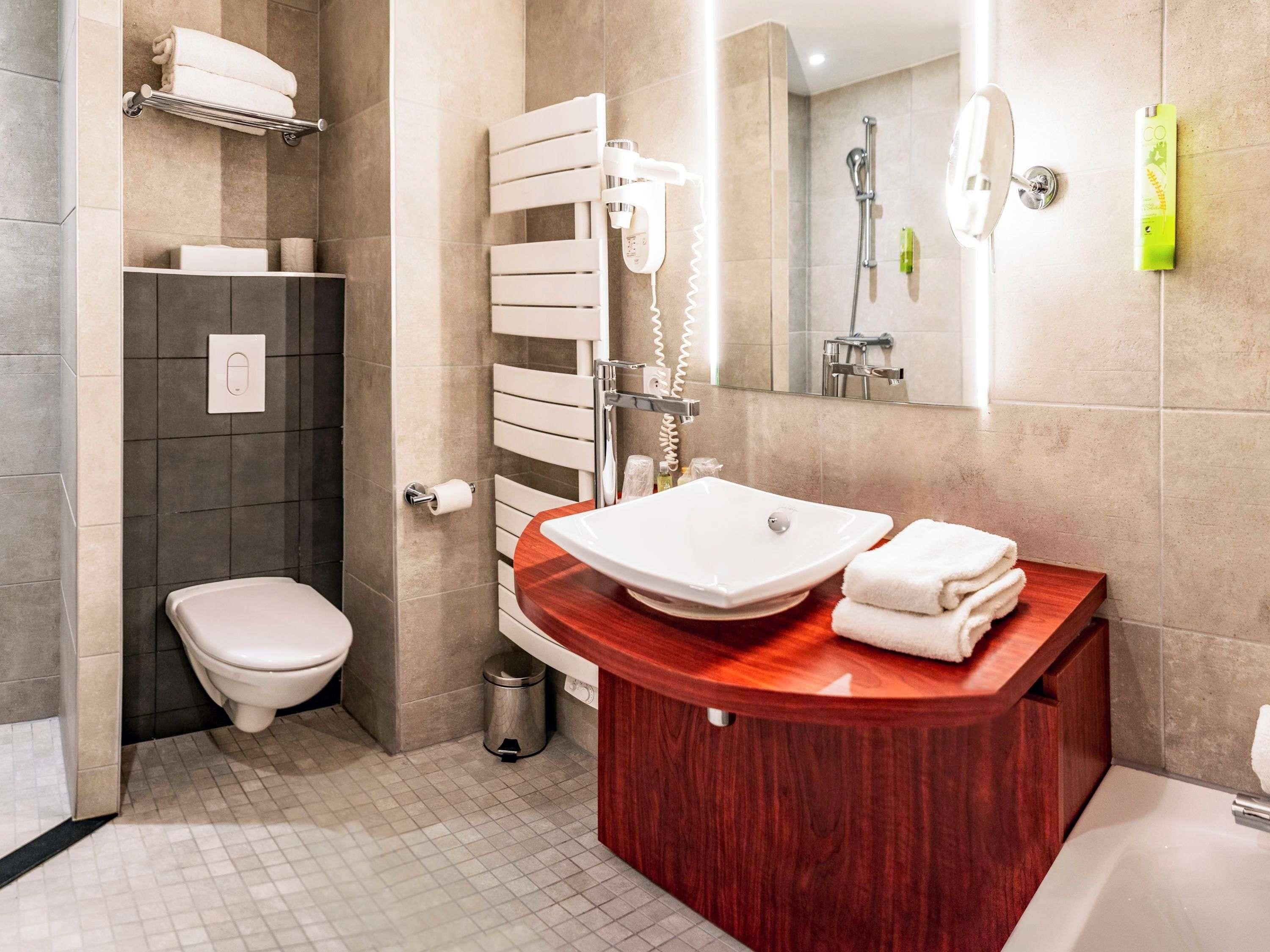 A modern bathroom with a toilet, a sink, a shower, and a mirror.