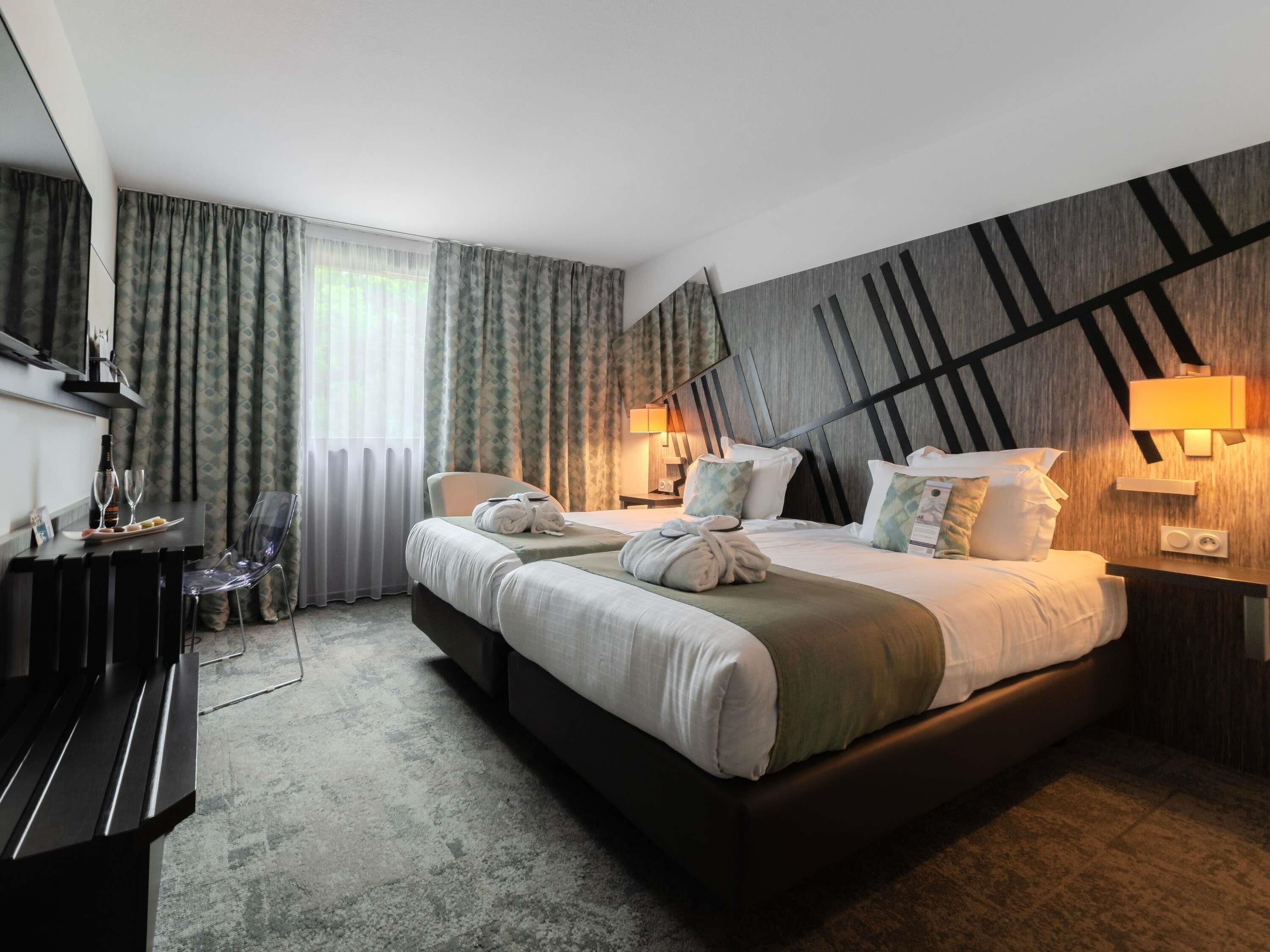 A hotel room with a large bed, two bedside tables, a desk with a chair, and a TV.