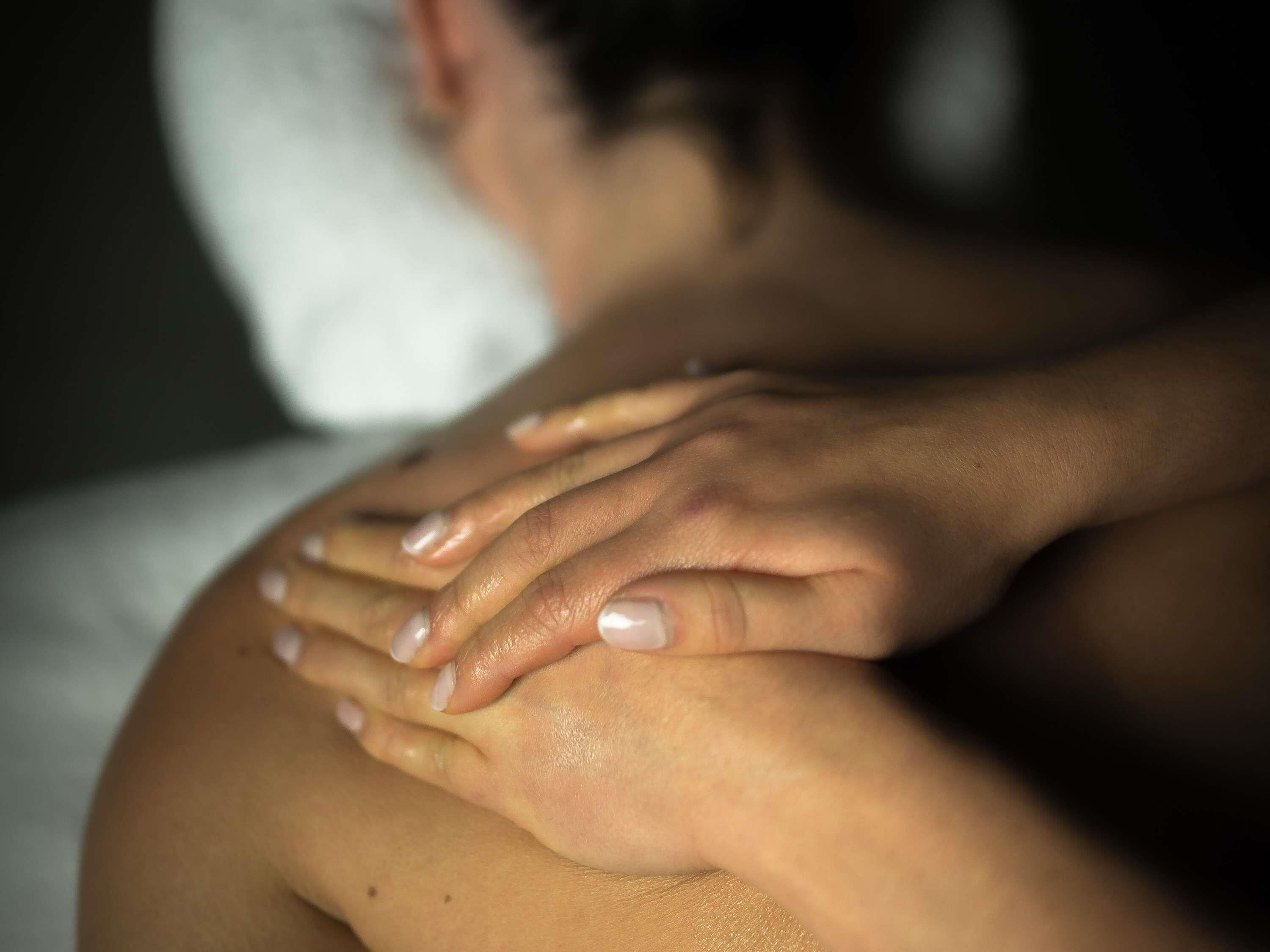 Gros plan sur des mains effectuant un massage sur le dos d’une personne.