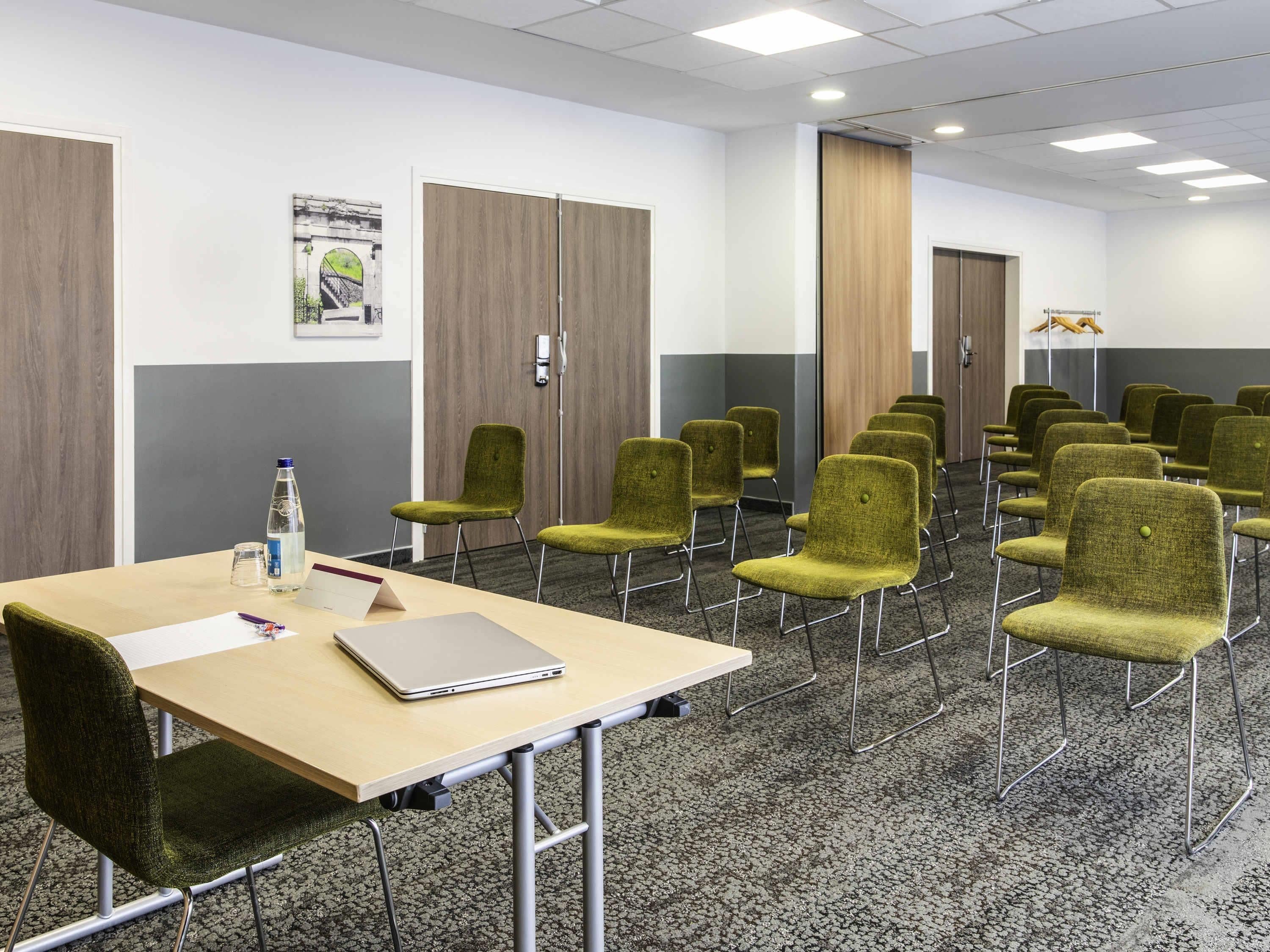 A conference room with a long table, multiple chairs, and a laptop.
