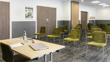 A conference room with a long table, multiple chairs, and a laptop.
