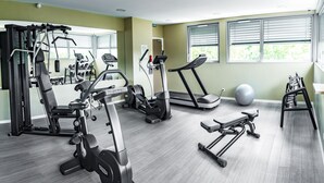 Un gimnasio con equipo de ejercicio variado, incluyendo cinta de correr, elíptica y máquinas de pesas.