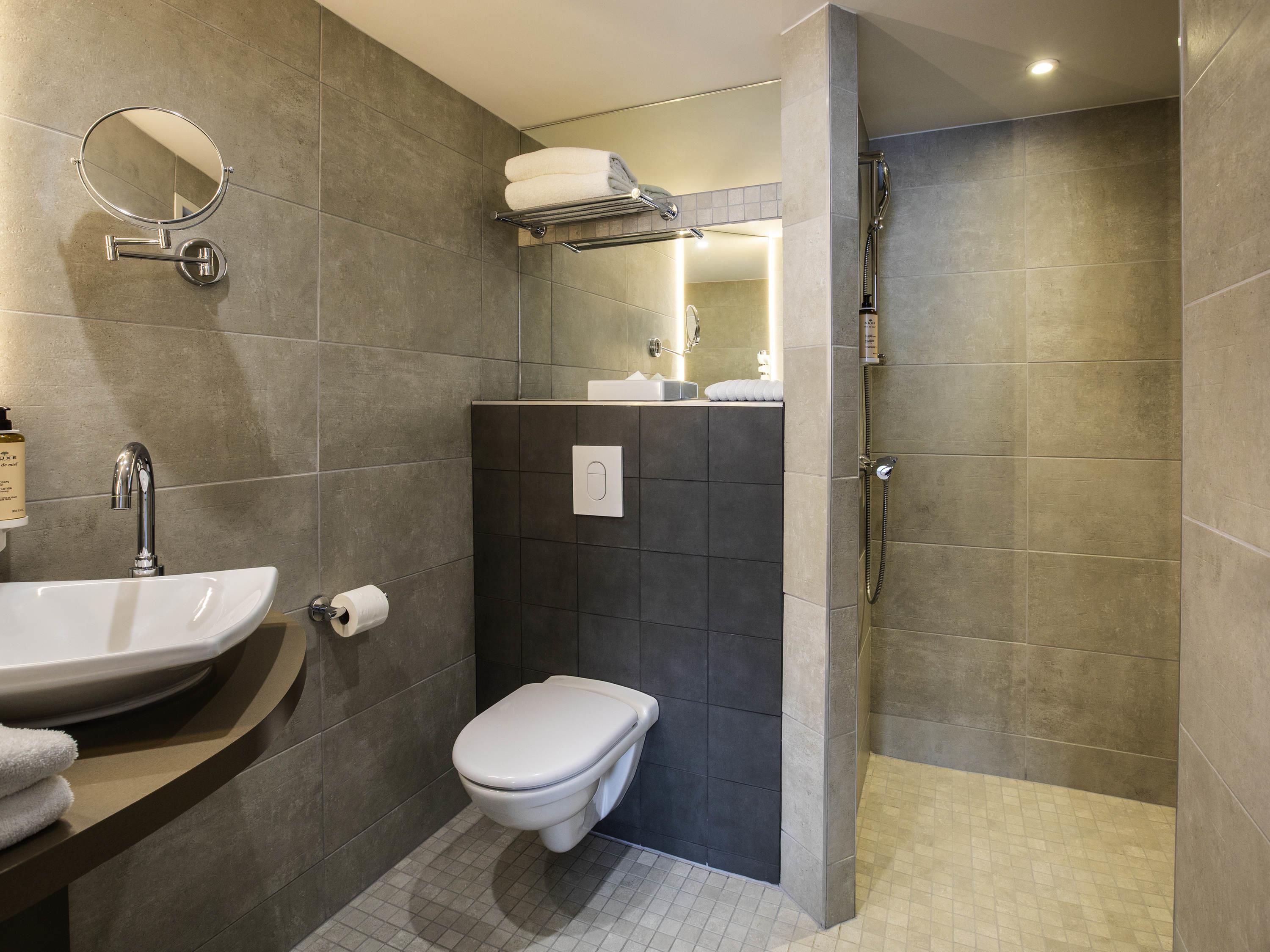Un baño moderno con lavamanos, inodoro y ducha a ras de suelo.