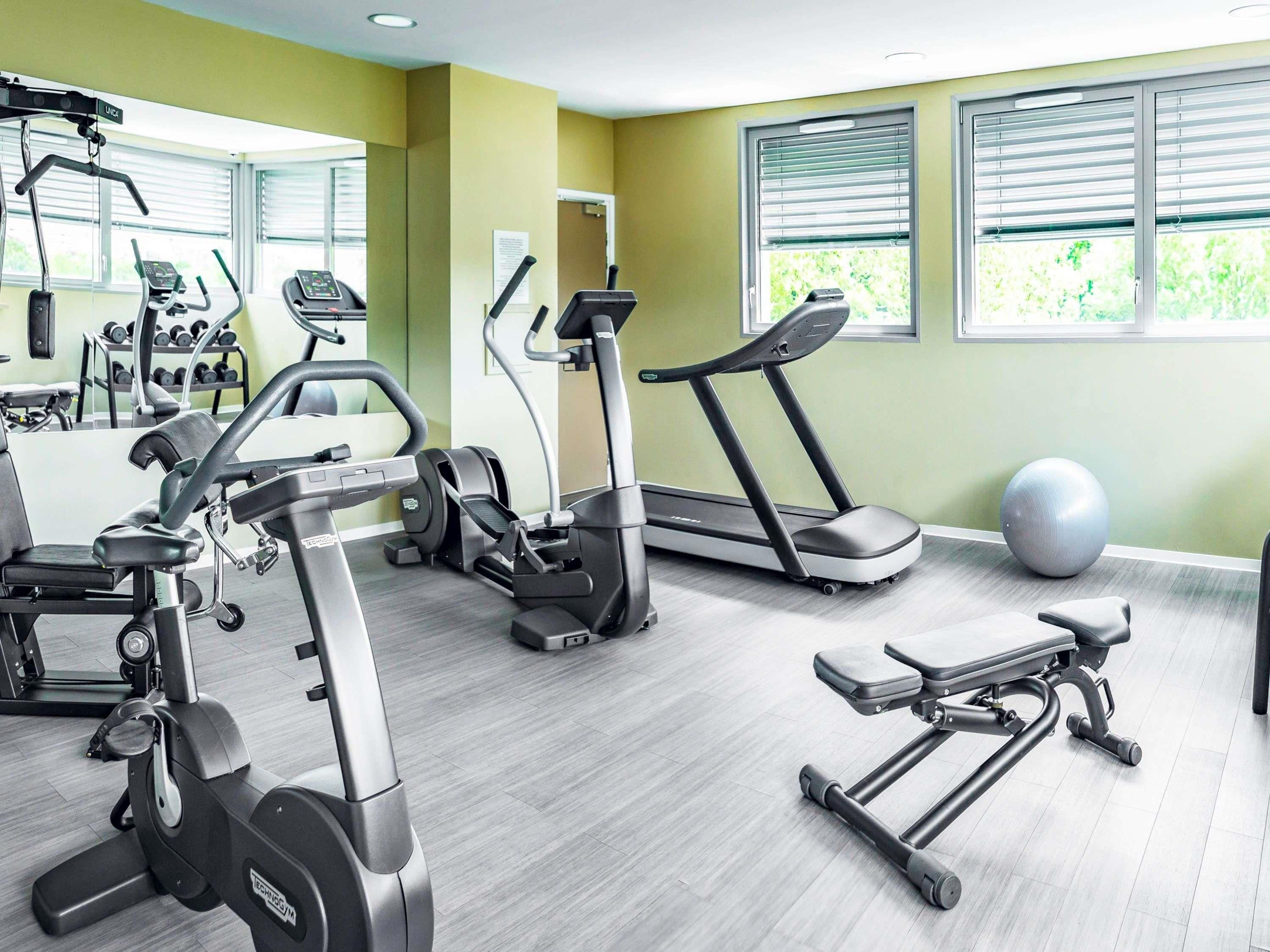 Un gimnasio con equipo de ejercicio, incluyendo cintas de correr, una elíptica y una máquina de remo.