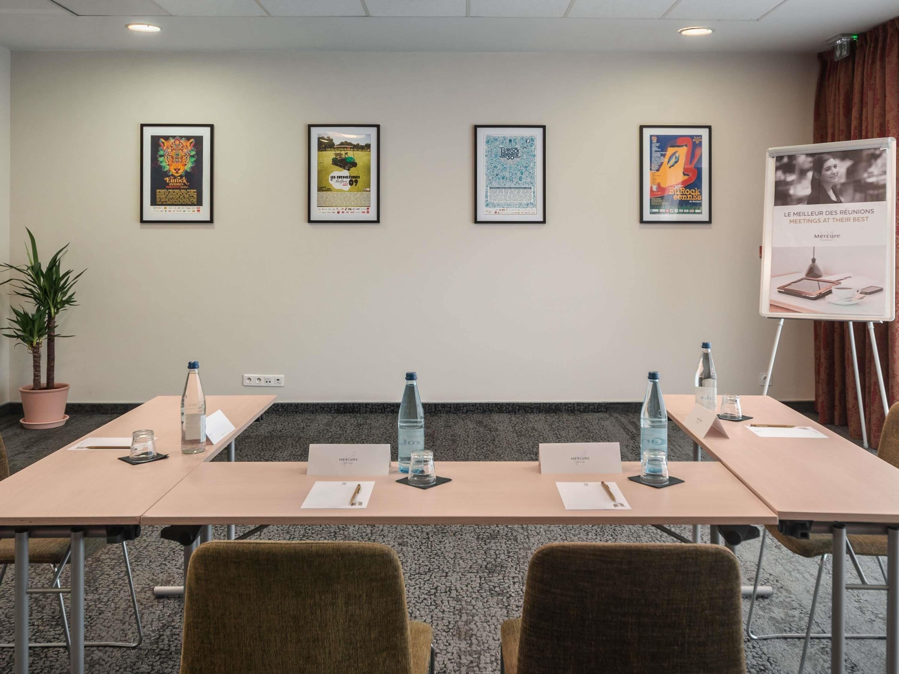 A conference room with a long table, chairs, water bottles, name tags, and framed posters on the wall.