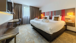 Een hotelkamer met een groot bed, een bureau, een stoel en een televisie.