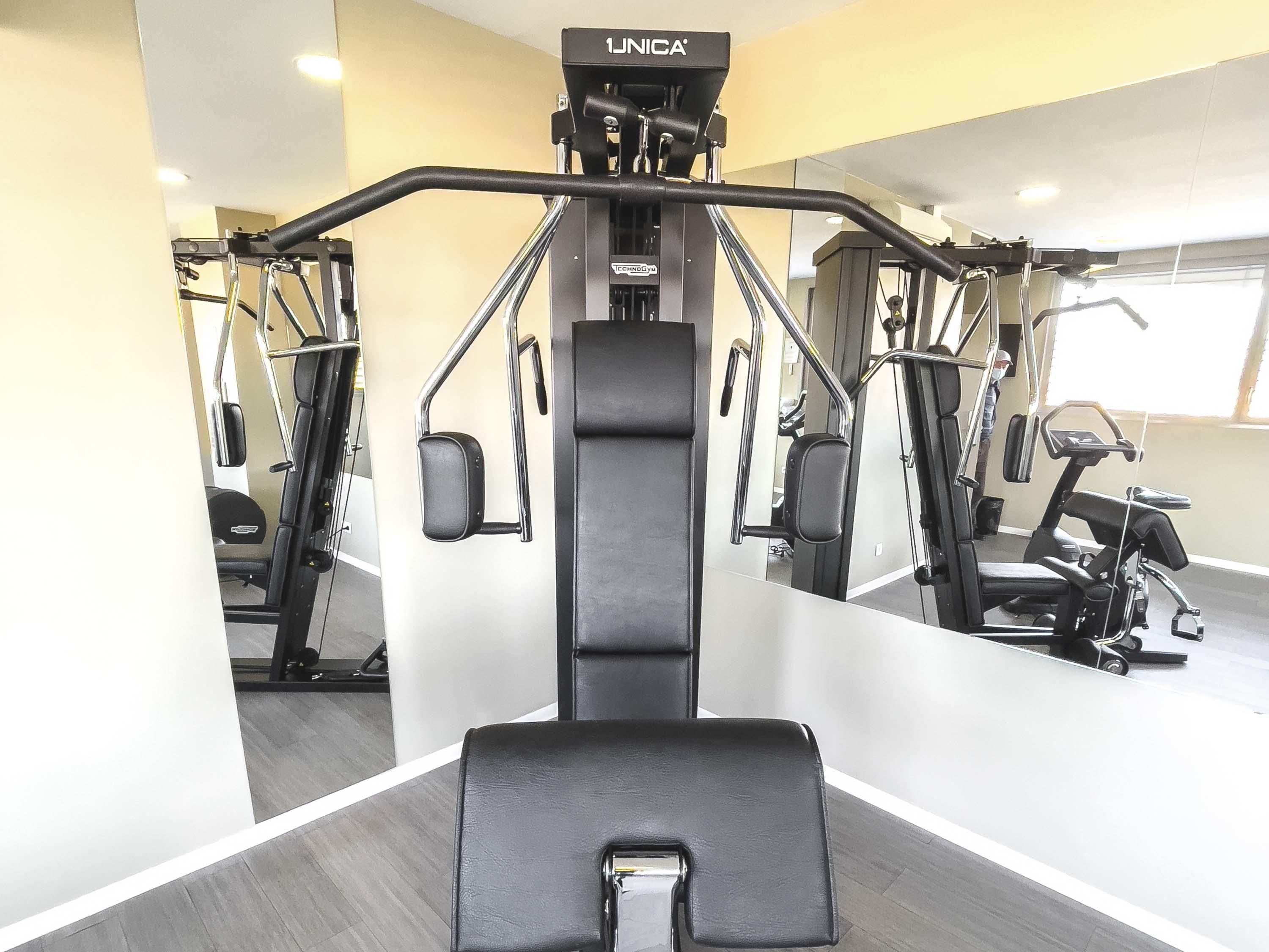 A gym with a mirrored wall, a pull-up bar, and a bench.