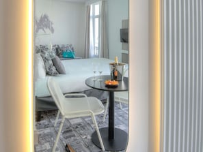 A hotel room with a bed, a table with two glasses and a bottle of champagne, and a chair. - Ibis Styles Nice Centre Gare (Nice)