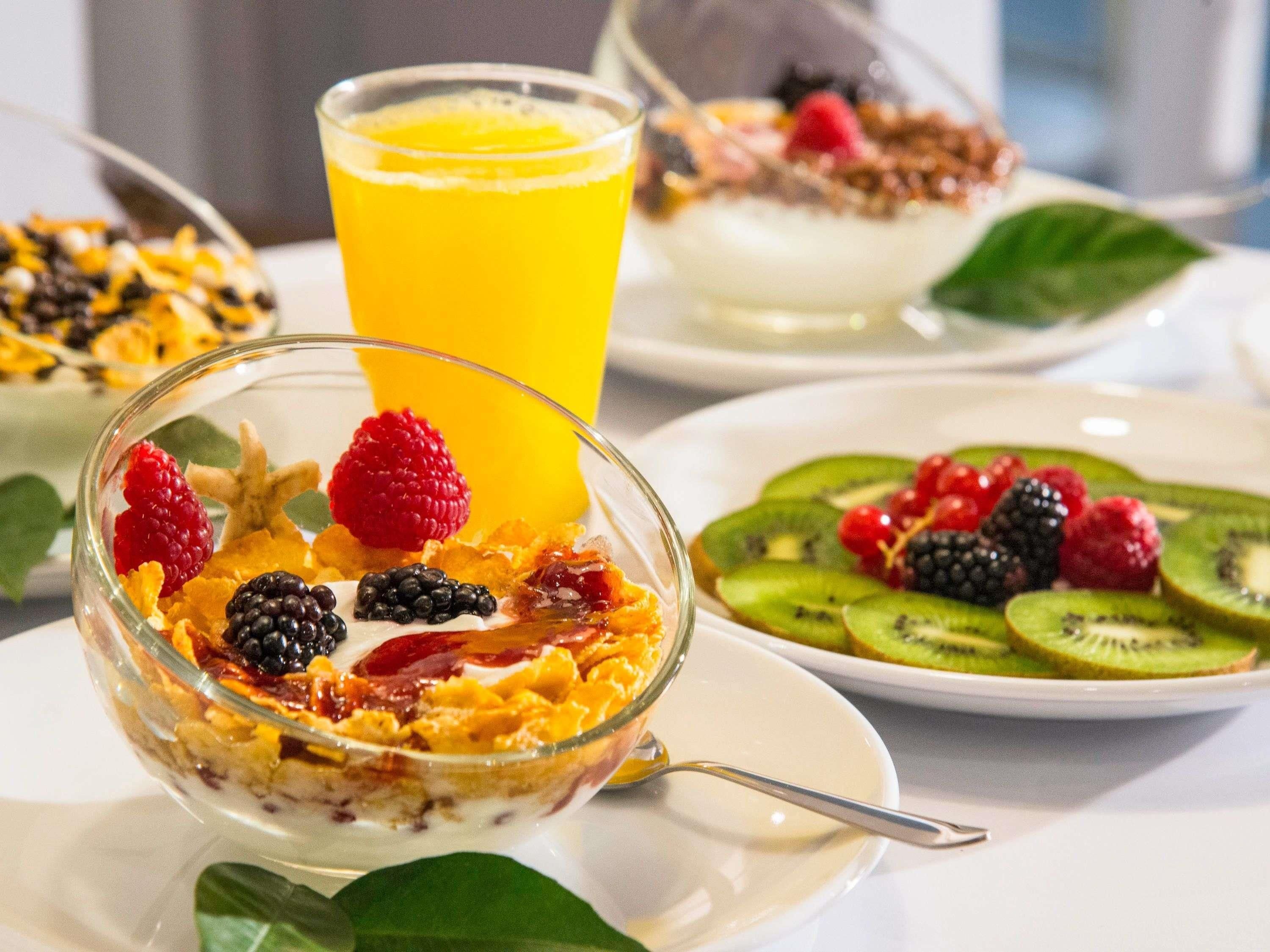 A breakfast setting with a bowl of cereal topped with berries and a glass of orange juice.